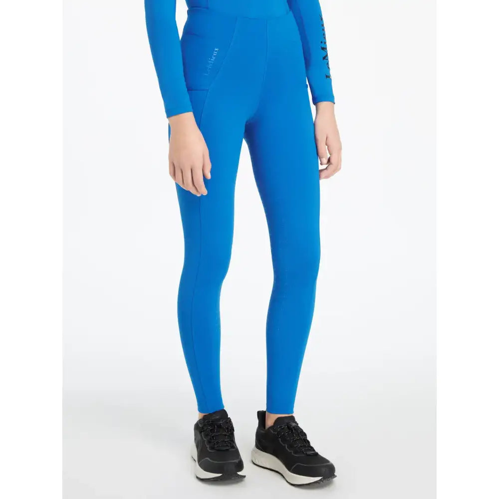 Bright blue form-fitting lemieux young rider orla pull ons benetton blue leggings with long sleeves and subtle thigh logo
