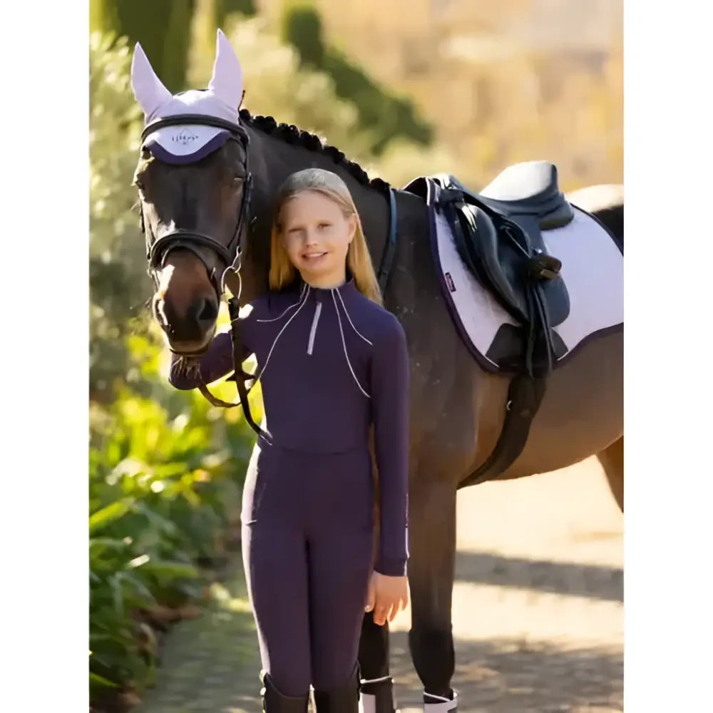 The girl wears a navy blue lemieux young rider orla pull ons riding suit with white zipper accents in juniper style