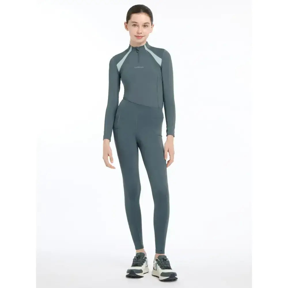 A sleek dark gray lemieux young rider orla long-sleeved top with light gray shoulder panels and subtle chest logo