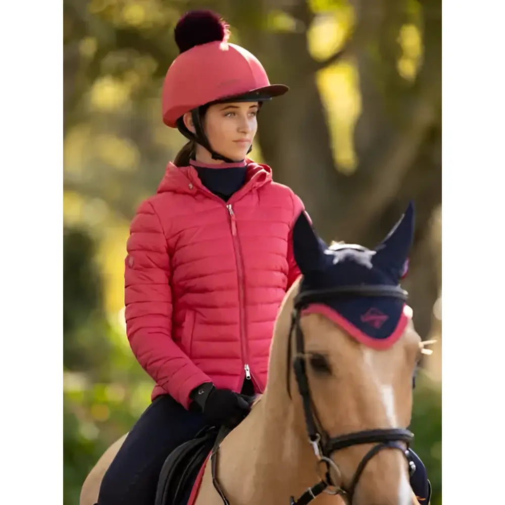 A vibrant pink quilted lemieux young rider helmet with a matching pom-pom complements the ruby puffer jacket cranberry