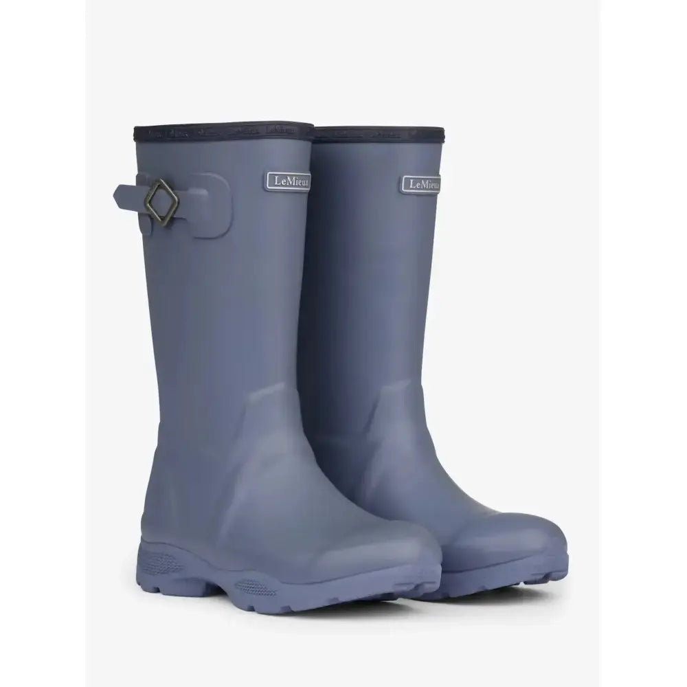 A pair of matte gray lemieux young rider wellies jay blue with black reinforced top edge and silver buckle strap on the side