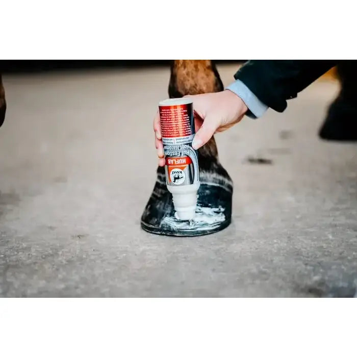 Leovet hoof lab hoof hardener in white and red can being applied to dark brown horse hoof to protect nail holes