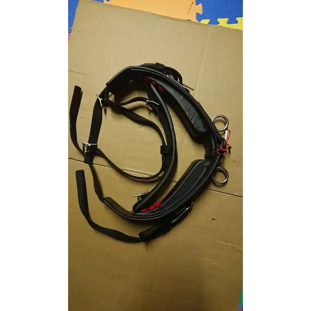 Black leather harness with red stitching and metal hardware from libby’s driving saddle featuring webbing tugs and belly band