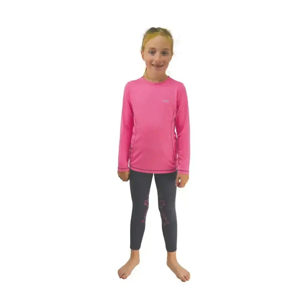 A young girl wearing a bright pink little rider base layer with subtle panels and dark star-patterned leggings in riding apparel
