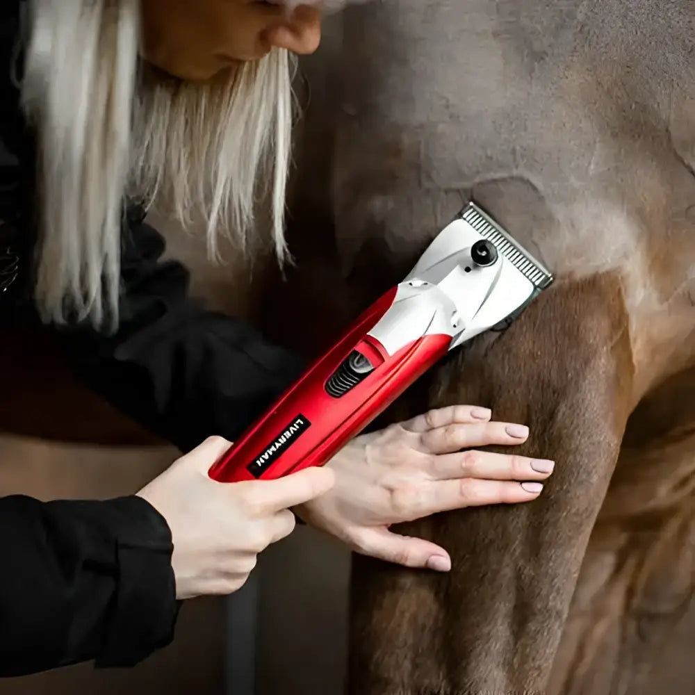 Red and silver liveryman black beauty clipper with battery pack trimming a horse’s coat for smooth grooming