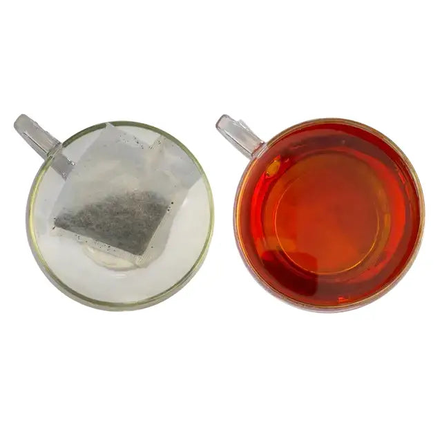 Clear glass teacup with amber tea and unbrewed tea bag showcasing miles tea decaffeinated teabags from west country