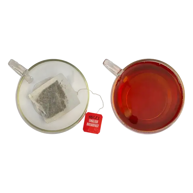 Red miles english breakfast tea bag sits next to a glass of brewed red tea in breakfast envelope teabags pack