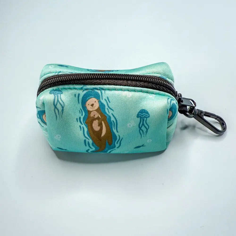 Turquoise fabric otterly lovely poo bag holder with otter and jellyfish design, black zipper, metal clip for easy access and stress-free cleanups