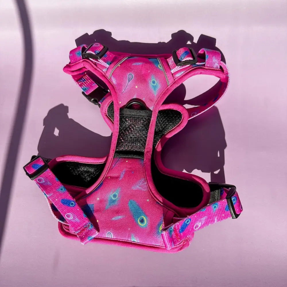 A vibrant pink tactical dog harness with peacock feather print and black mesh panels for pup chic comfort