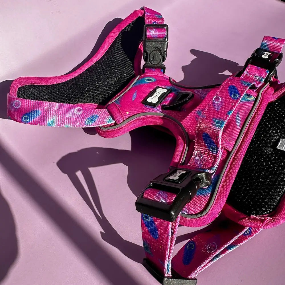 Pink tactical dog harness with peacock feather print, black mesh padding, and adjustable buckles for pup chic style