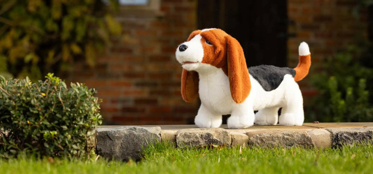 A plush beagle toy with long brown ears, a white body, and black patch on its back.