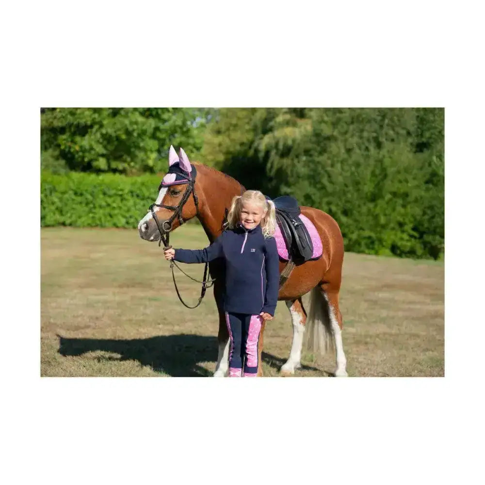A young girl in navy and pink stands with a chestnut horse wearing a pony fantasy head collar and lead rope set