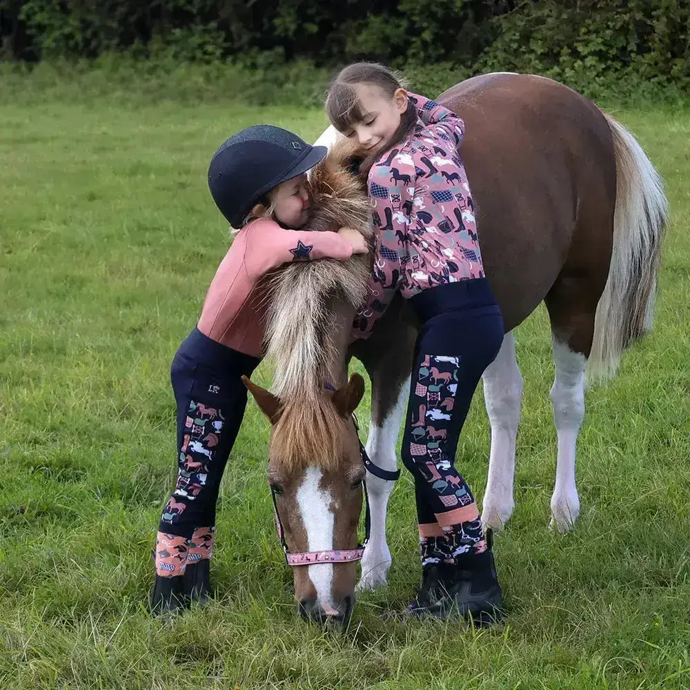 A brown and white pony wearing a pink passion head collar and lead rope set grazing in a grassy field