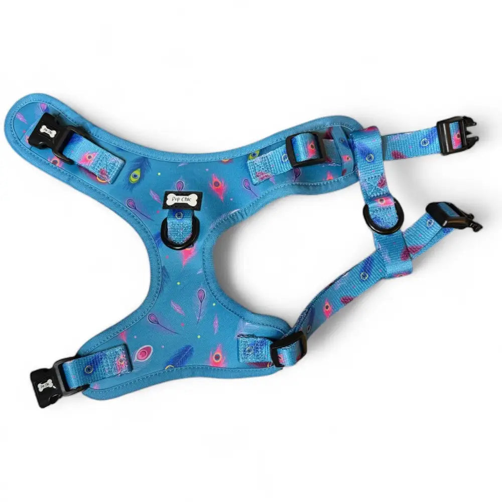 A vibrant blue power peacock step-in adjustable small dog harness with pink feather pattern and black buckles