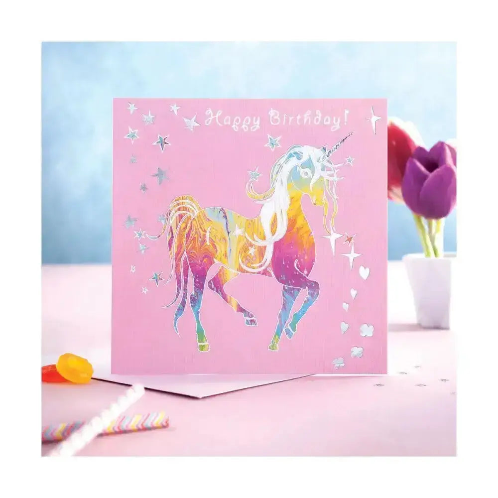 A vibrant pink prancing myth card birthday glitter unicorn with silver star and heart cutouts and happy birthday text