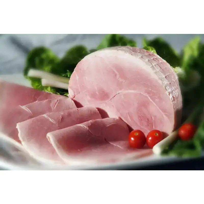 Sliced pink premium devon ham arranged on a plate with fresh greens and cherry tomatoes in 10 slices pack