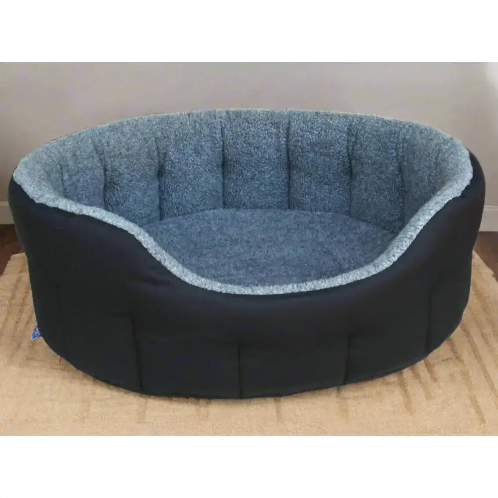 A cozy premium oval bolster dog bed with black outer shell and heavy duty fleece lined blue interior, machine washable
