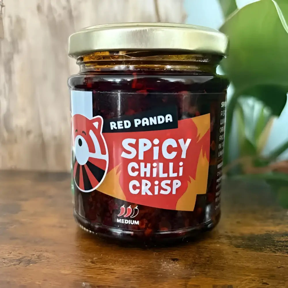A glass jar of red panda spicy chilli crisp with a gold lid and vibrant red panda chilli label