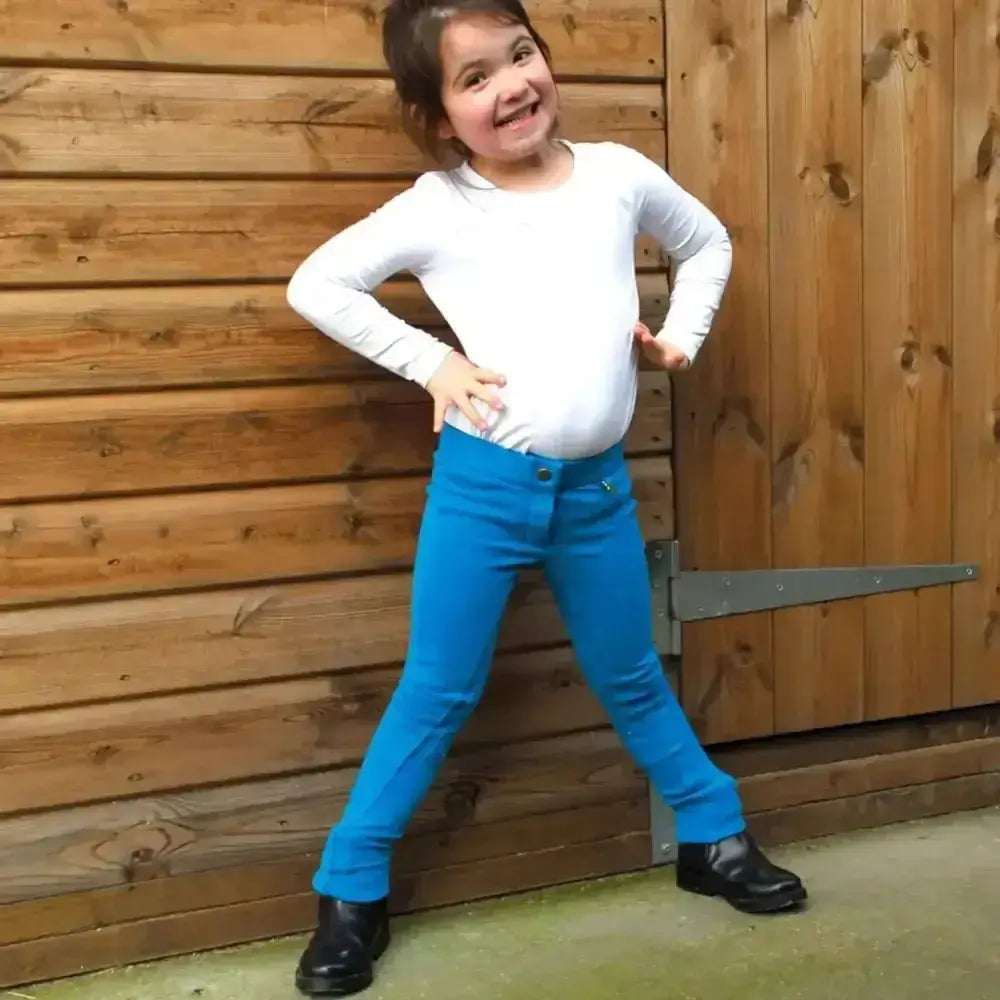A young girl wearing bright blue rhinegold childs jodhpurs essential everyday with inside pocket and white top