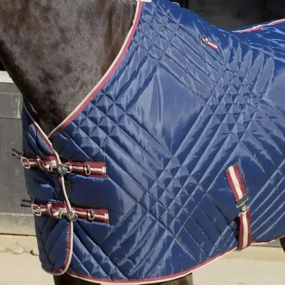 Blue quilted horse blanket with red and white trim metal buckles and diamond stitch pattern rhinegold dallas chevron stable rug