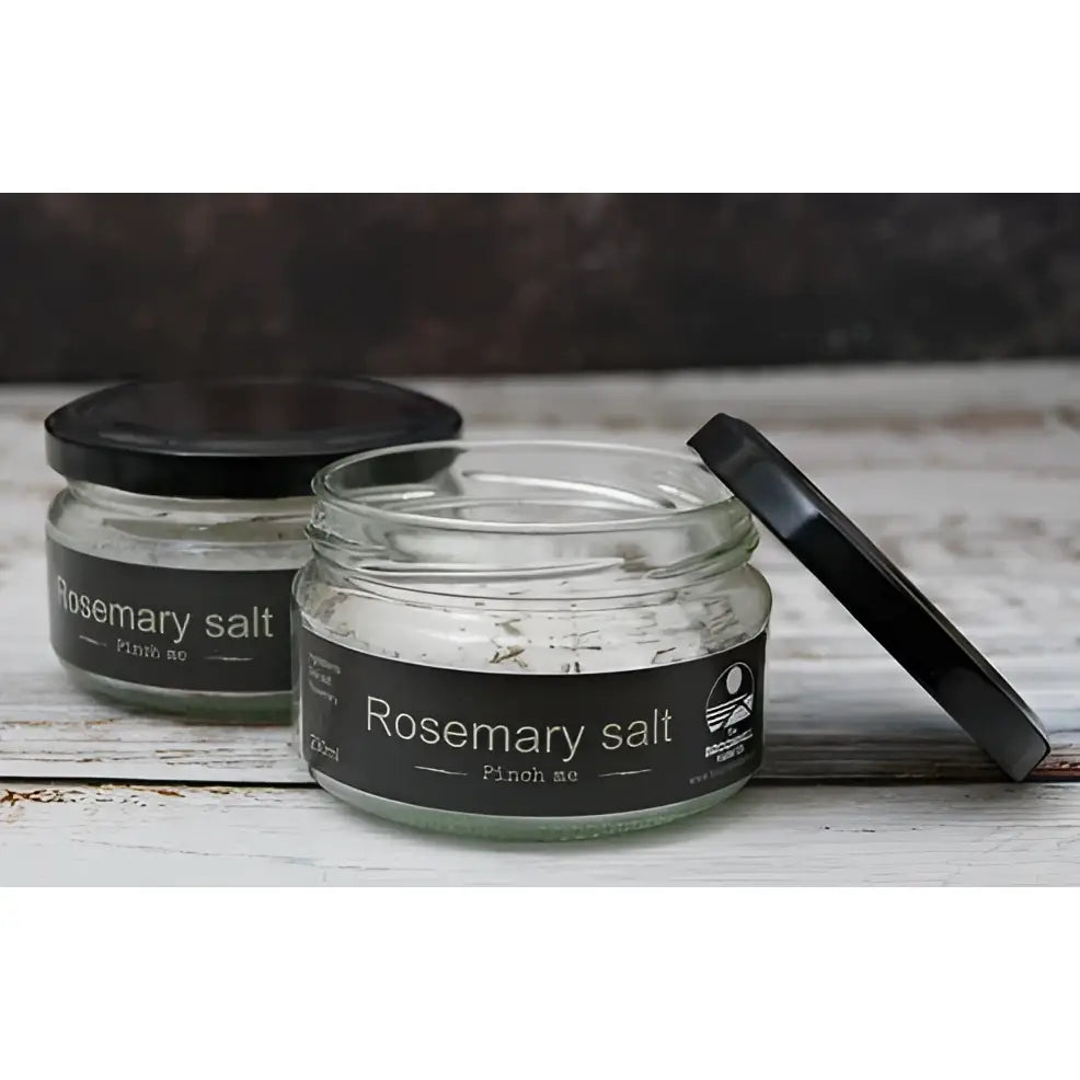 Clear glass jar with black lid containing rosemary herb infused salt by broomhill farm co for seasoning meals