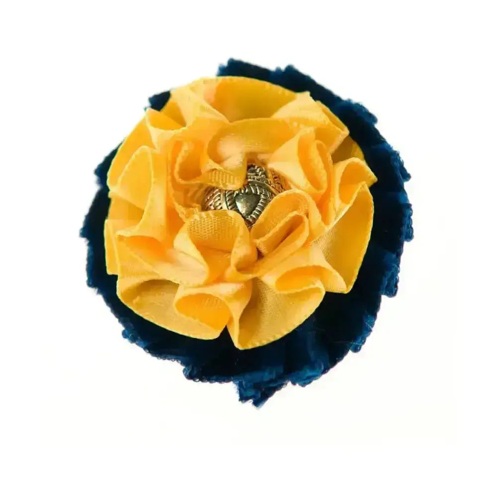 A vibrant yellow fabric flower brooch with navy blue ruffled border and metallic heart center showquest newport buttonhole