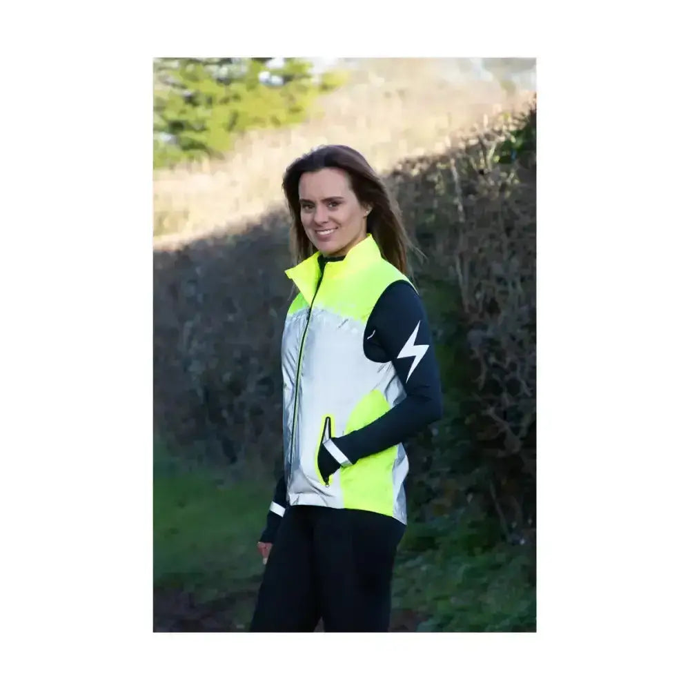 A woman wearing a neon yellow silva flash lightweight duo reflective gilet with silver panels and a black lightning bolt logo
