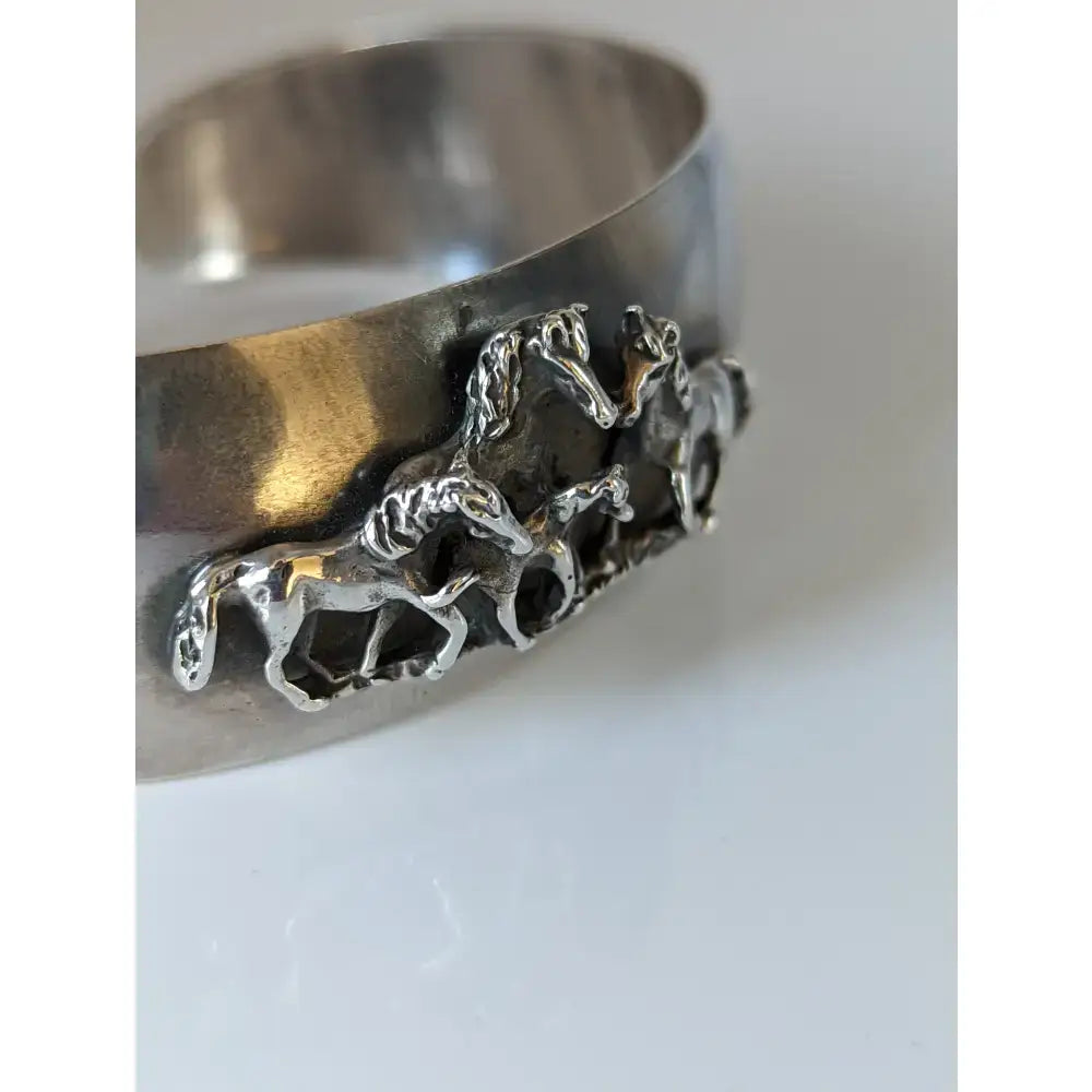 Silver steed herd bangle is a silver horse-themed cuff bracelet with a hammered finish perfect for equestrian jewelry fans