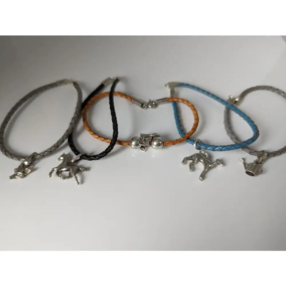 A collection of silver steed leather cord bracelets in gray black orange and blue with braided design and horse charms