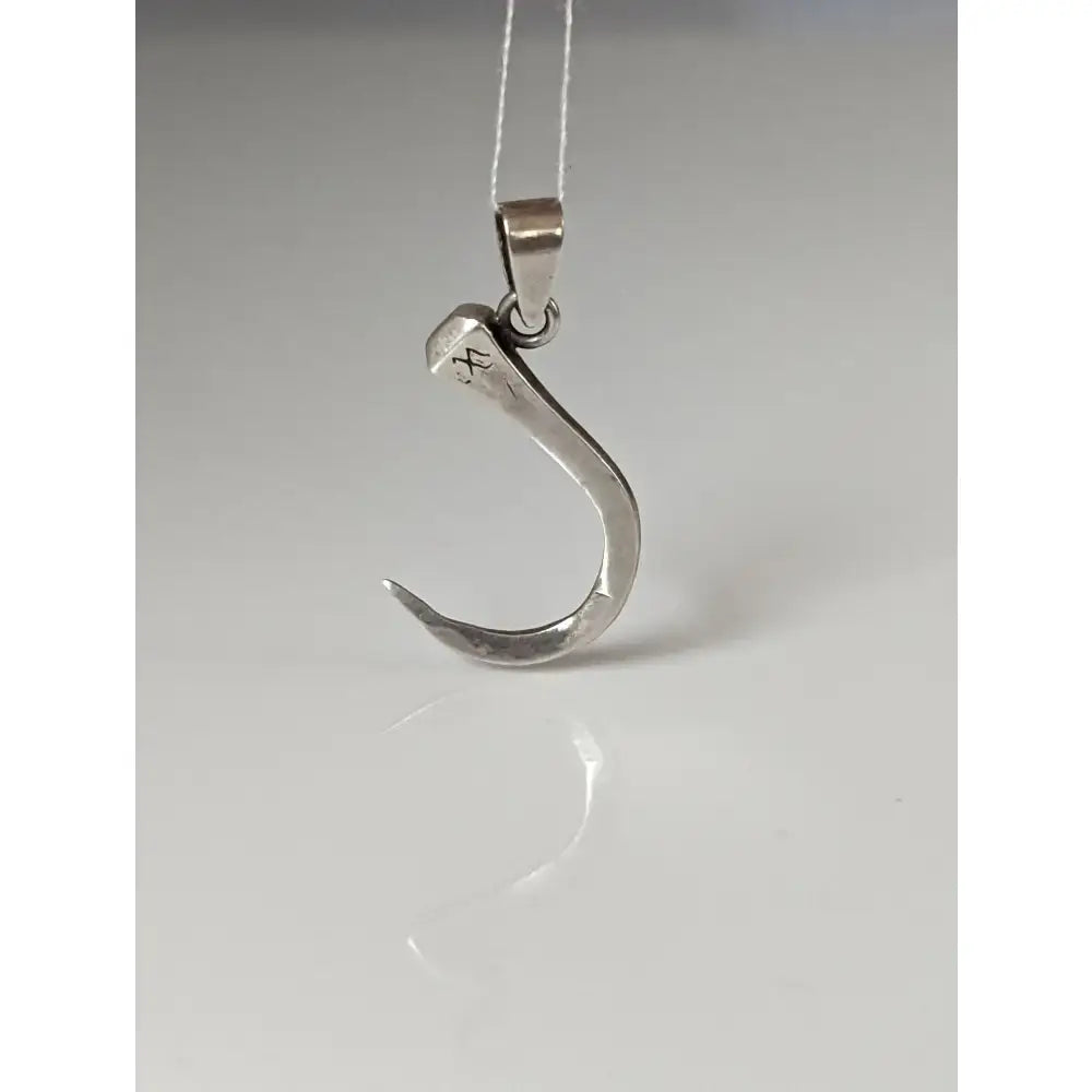 Silver steed curved horseshoe nail silver pendant with hammered texture and engraved markings near the top