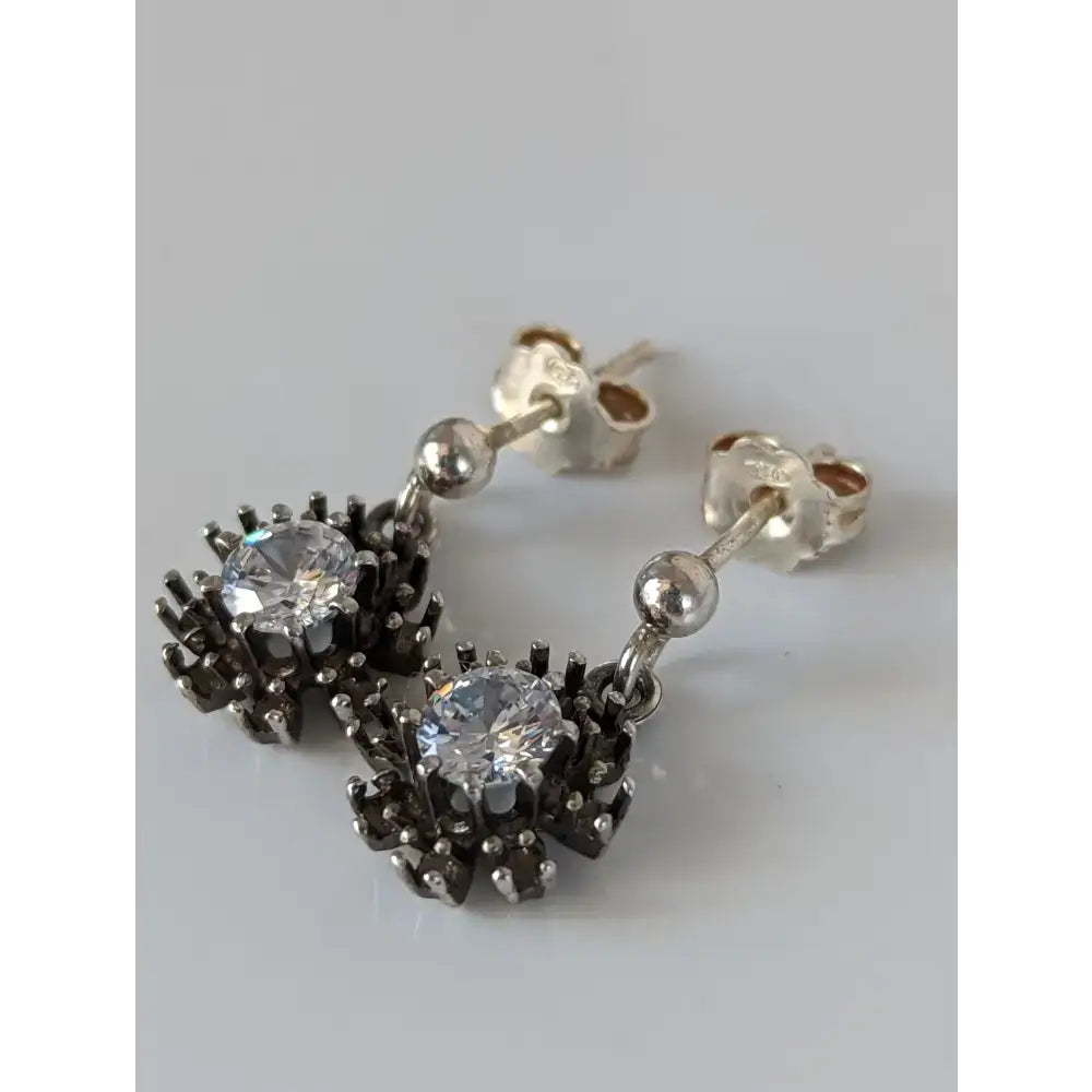 Silver steed dangling crystal sunflower stud earrings with clear crystal center and blackened metal floral design