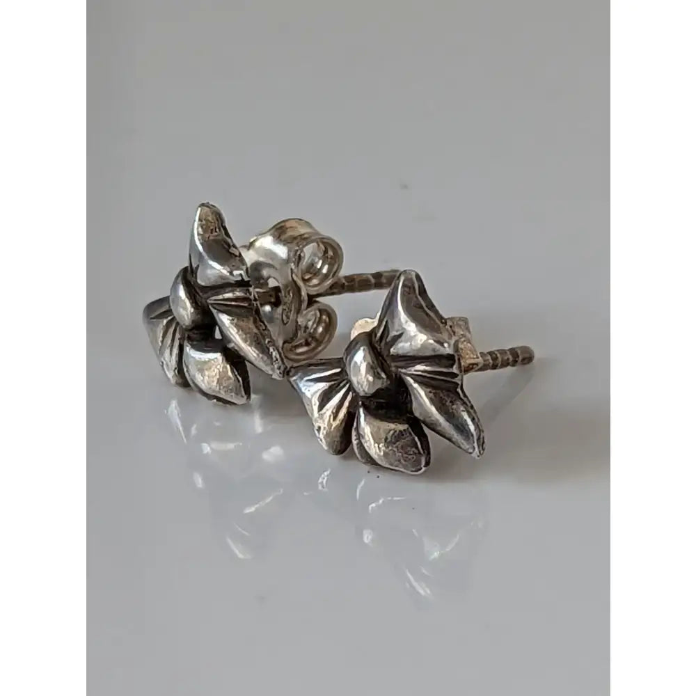 Silver steed detailed bow stud earrings with silver flower design and polished textured petals in 3d style
