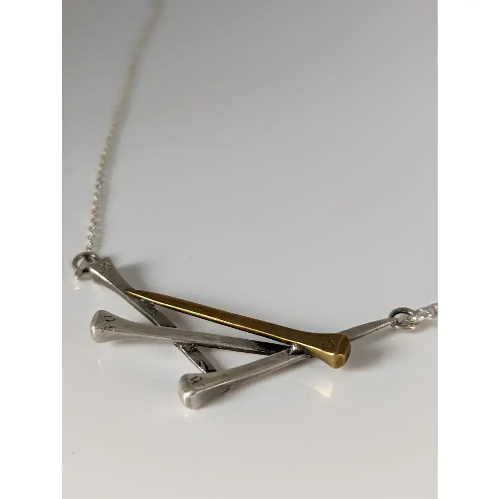 Silver steed elegant hoof nails necklace with a delicate silver chain and a pendant of one gold and two silver golf tees crossed