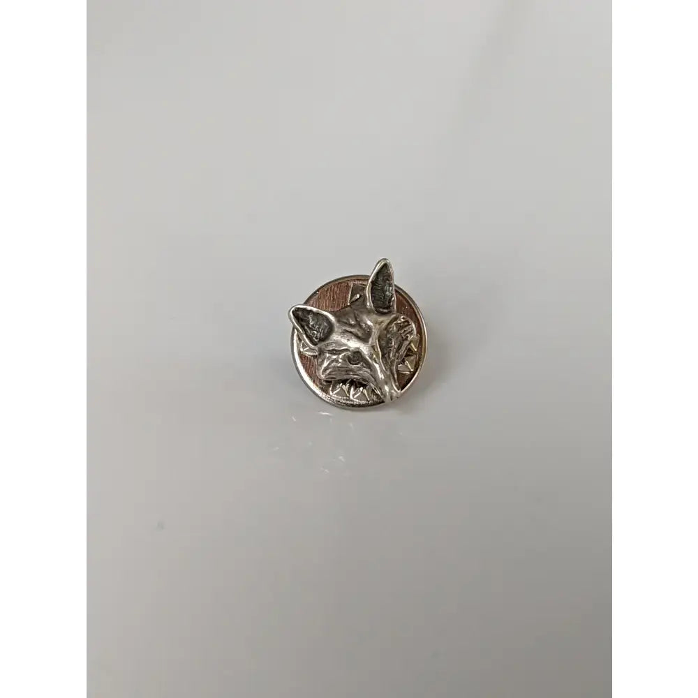 Silver steed fox head silver pin with detailed facial features and pointed ears on a copper-toned background