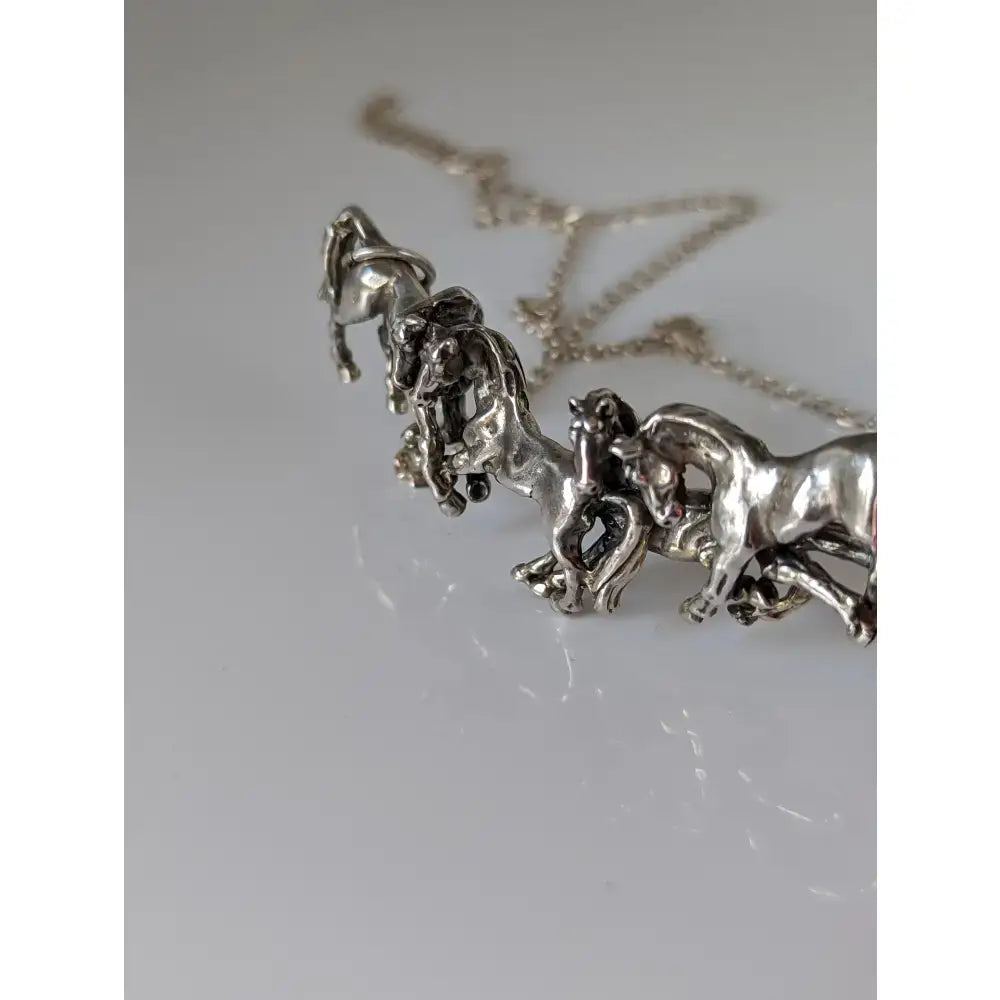 Silver steed herd necklace featuring a silver necklace with a detailed sculpted pendant of multiple horses in motion