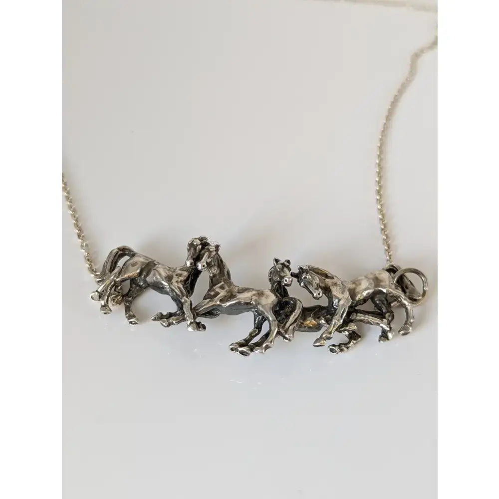 Silver steed herd necklace with a detailed silver pendant of four sculpted horses in dynamic motion