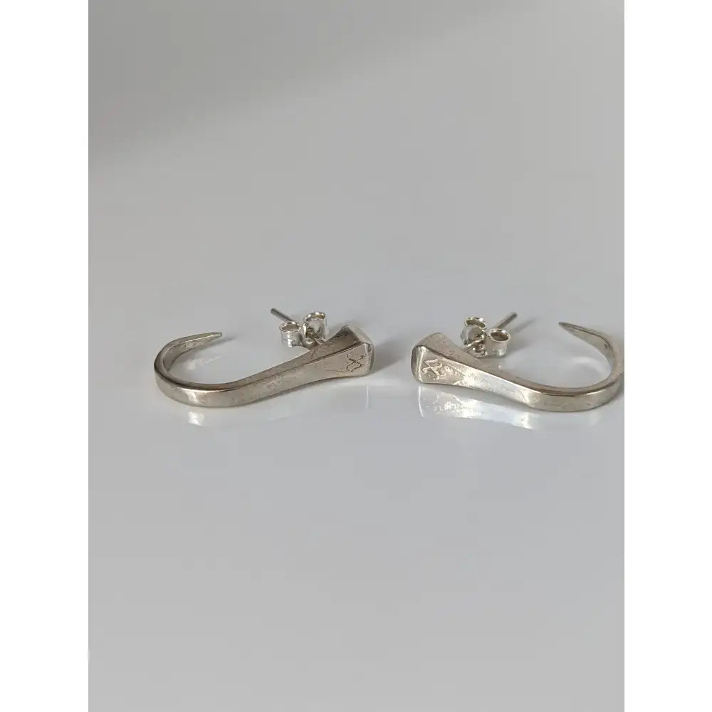 Silver steed hoofnail stud earrings feature silver nail-shaped hoops with hammered texture and subtle engraved details