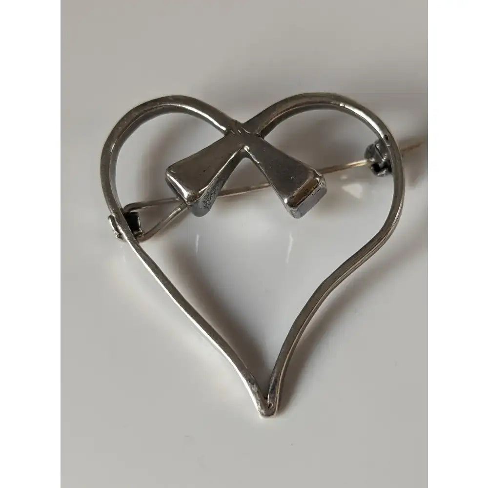 Silver steed horse heart brooch features a silver shoe nail heart with a bow detail perfect as a stock tie pin