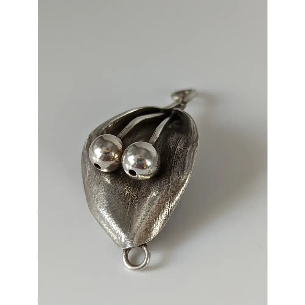 Silver steed leaf silver pendant with two polished beads nestled in textured sterling silver leaf design