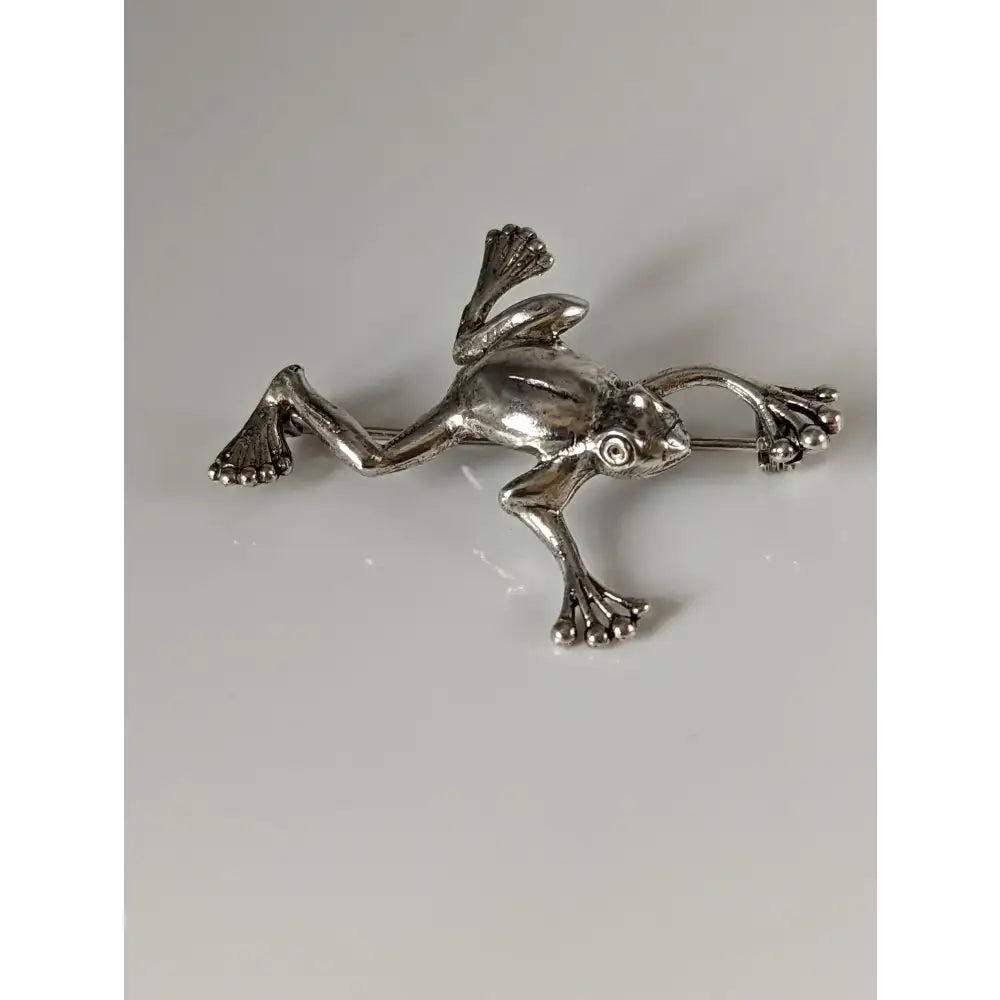 Silver steed leaping frog silver brooch with detailed articulated limbs and textured skin in silver equestrian jewelry style