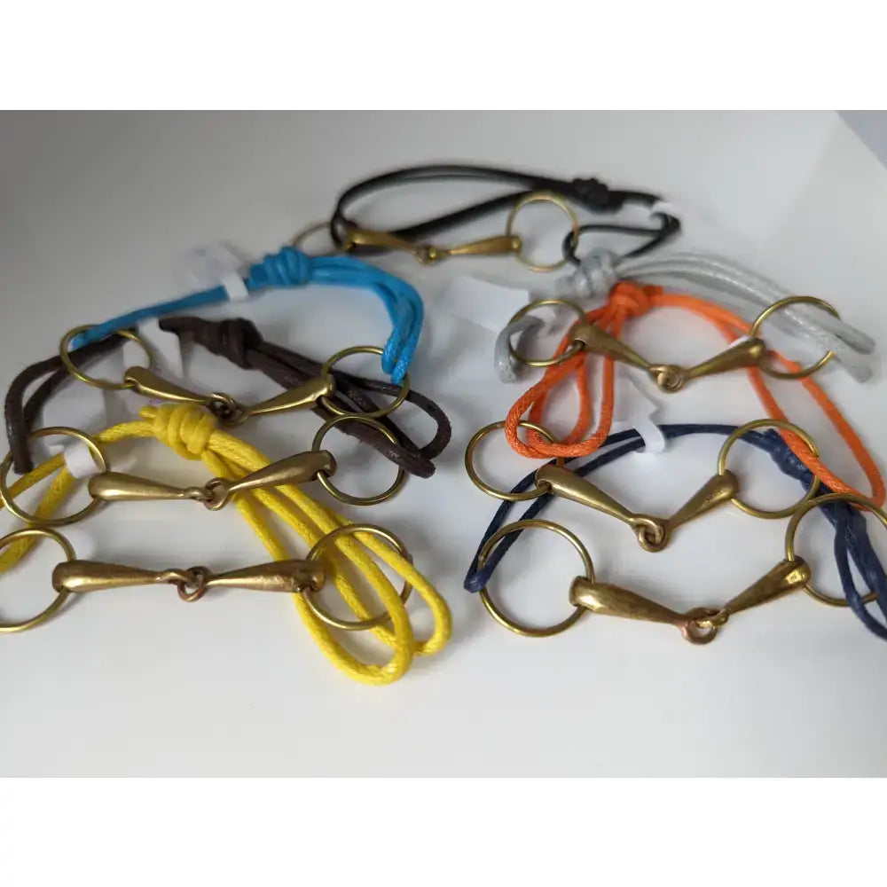 A colorful collection of silver steed leather snaffle cord bracelets with brass snaffle leather horsebit charms and gold rings