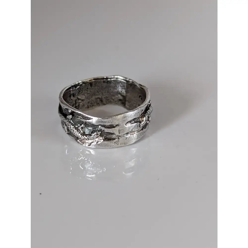 Silver steed lizard band is a silver-toned ring with a textured, handcrafted design featuring an embossed dragon motif