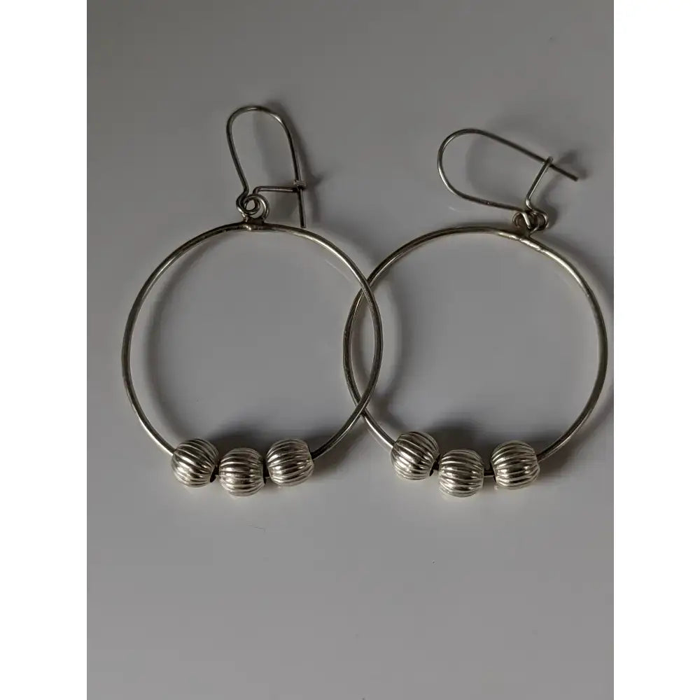 Silver steed loop buds dangling earrings featuring silver hoops with three textured sterling silver beads each