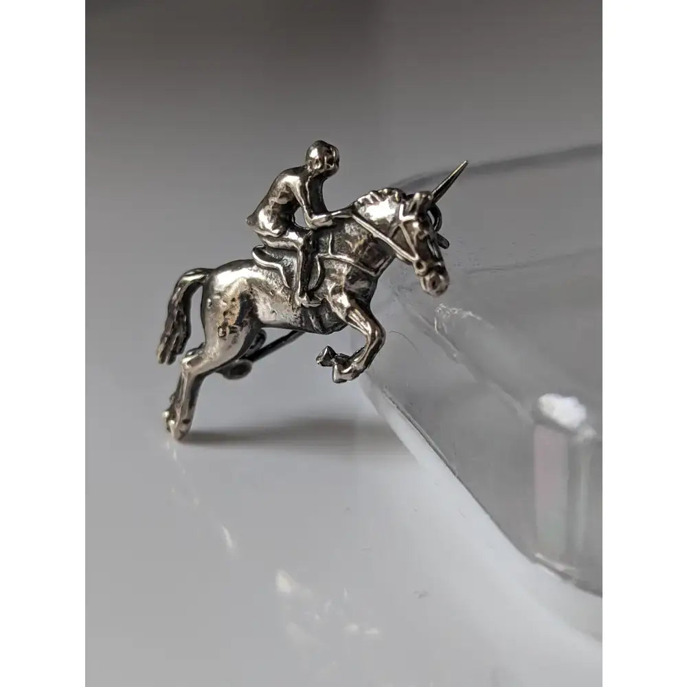Silver steed stock tie pin featuring a silver metallic jumper brooch of a jockey riding a unicorn horse