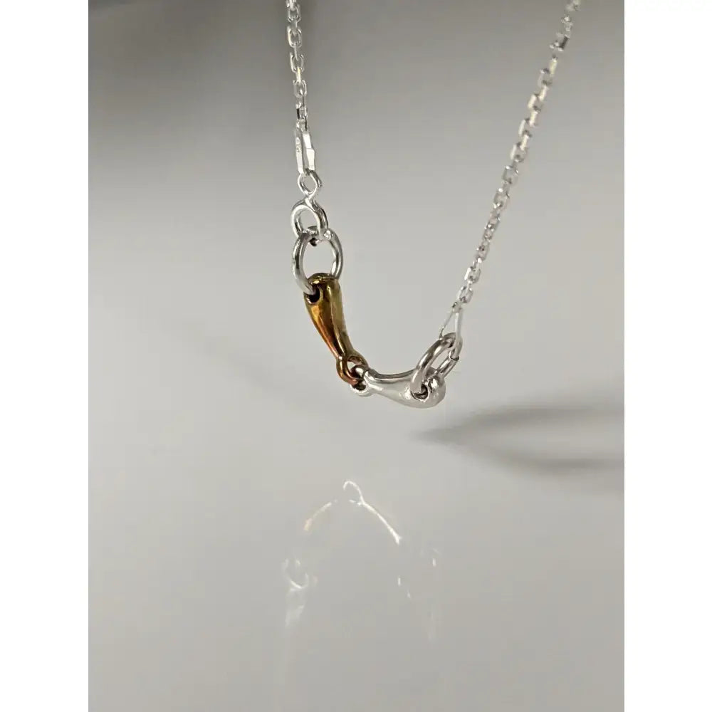 Silver steed snaffle necklace with a silver and gold-toned horsebit pendant and polished two-tone finish