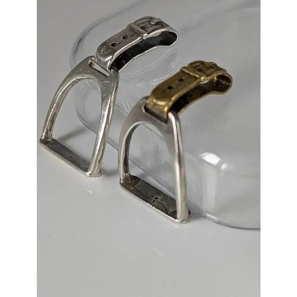 Silver steed stirrup silver pendant featuring silver and gold-toned horse saddle stirrups with metallic buckles