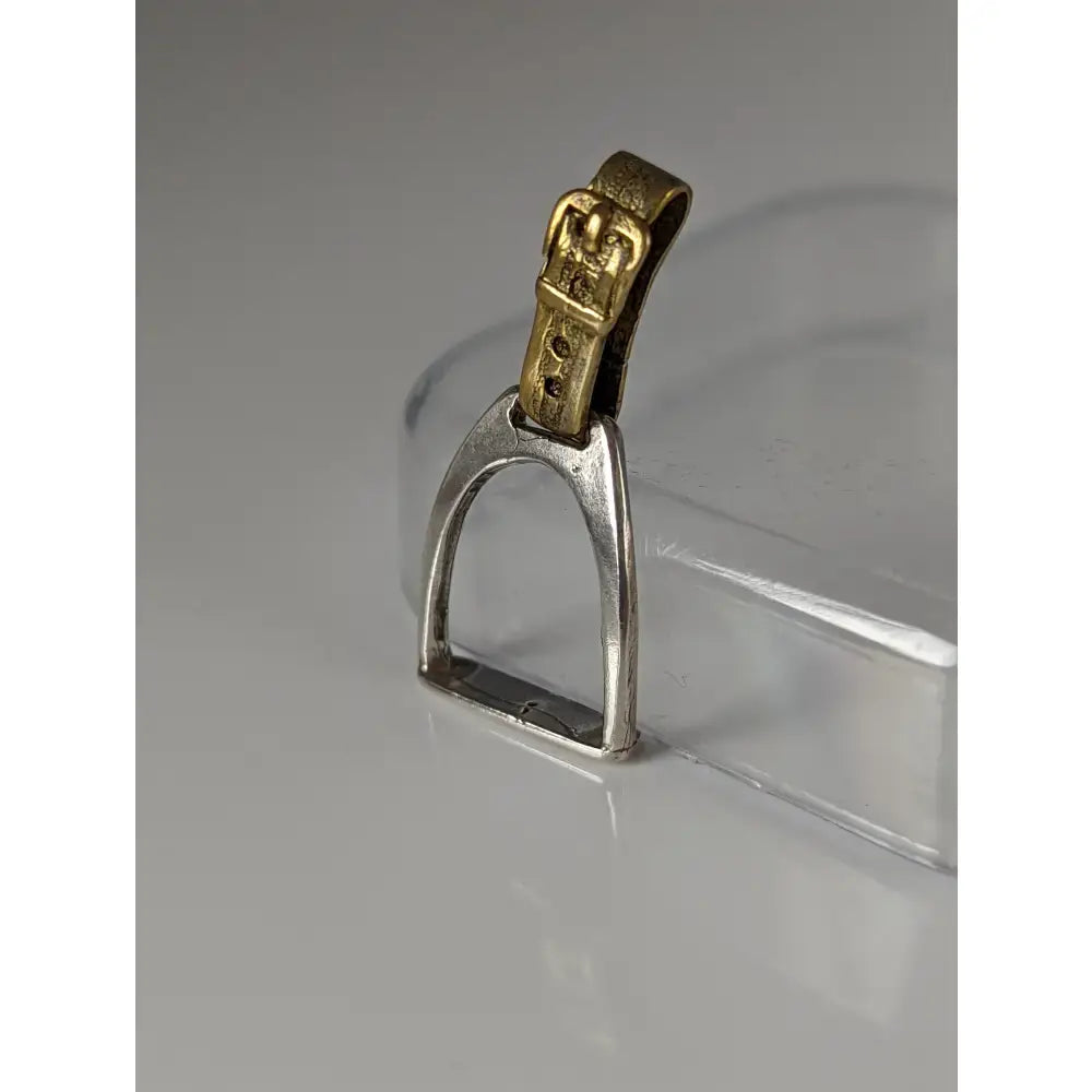 Silver steed stirrup silver pendant featuring a silver stirrup with gold-toned leather strap and buckle