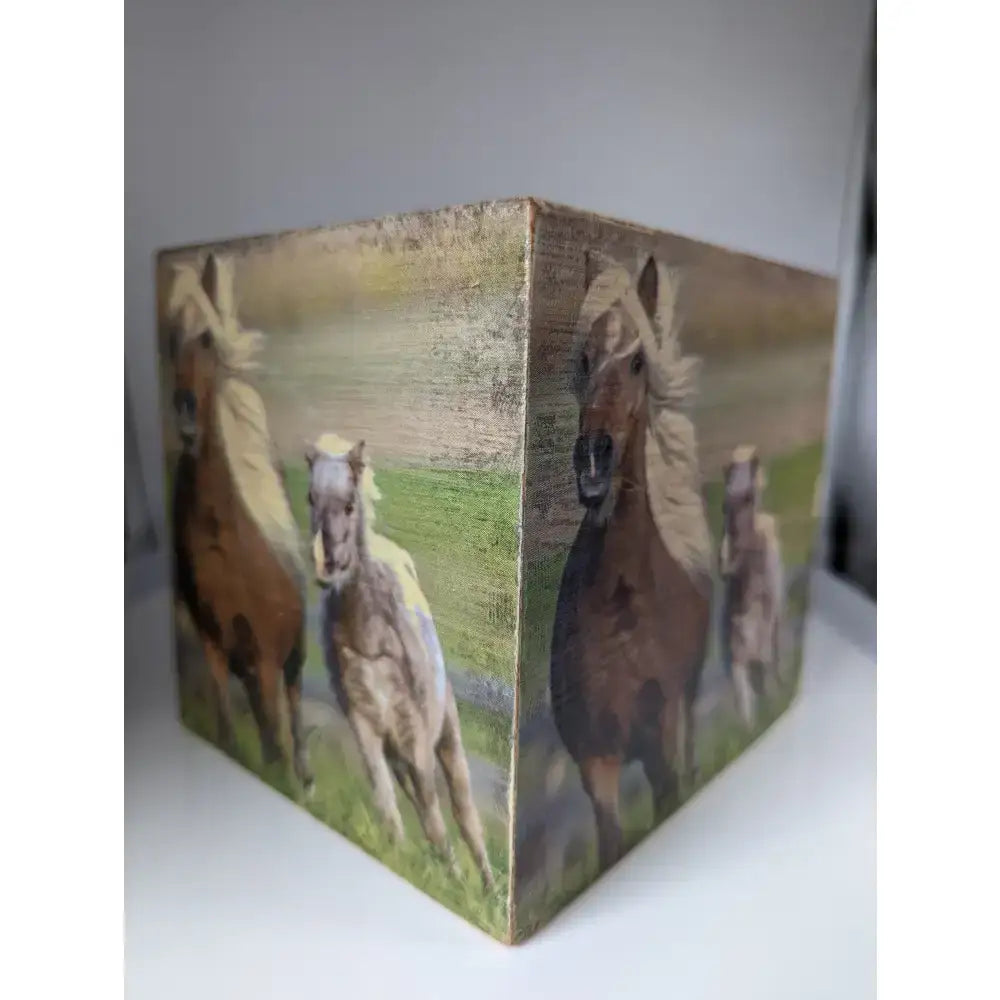 A rustic wooden silver steed tissue box with painted horses running across a grassy field design