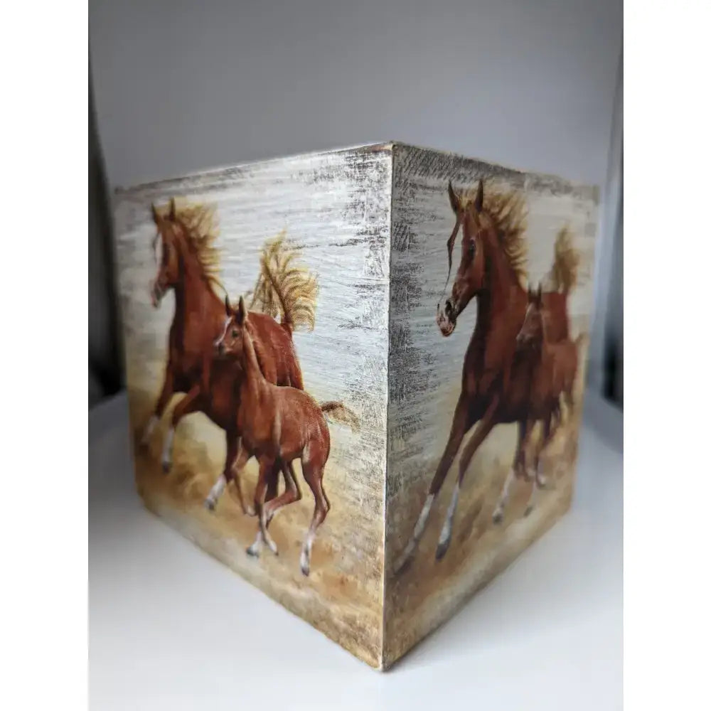 A cube-shaped silver steed tissue box featuring brown horses in motion on a textured white and beige background