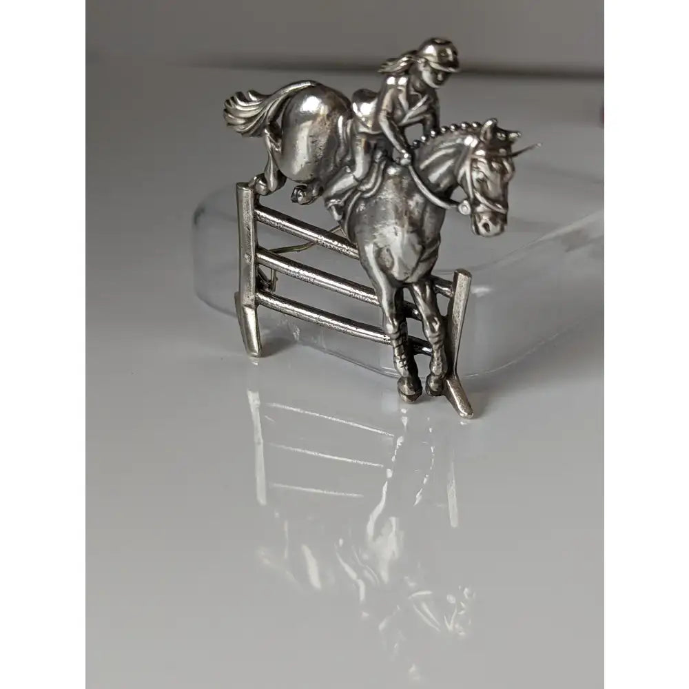 Silver steed triple bar jump stock tie pin featuring a silver jumping brooch with rider and horse mid-jump